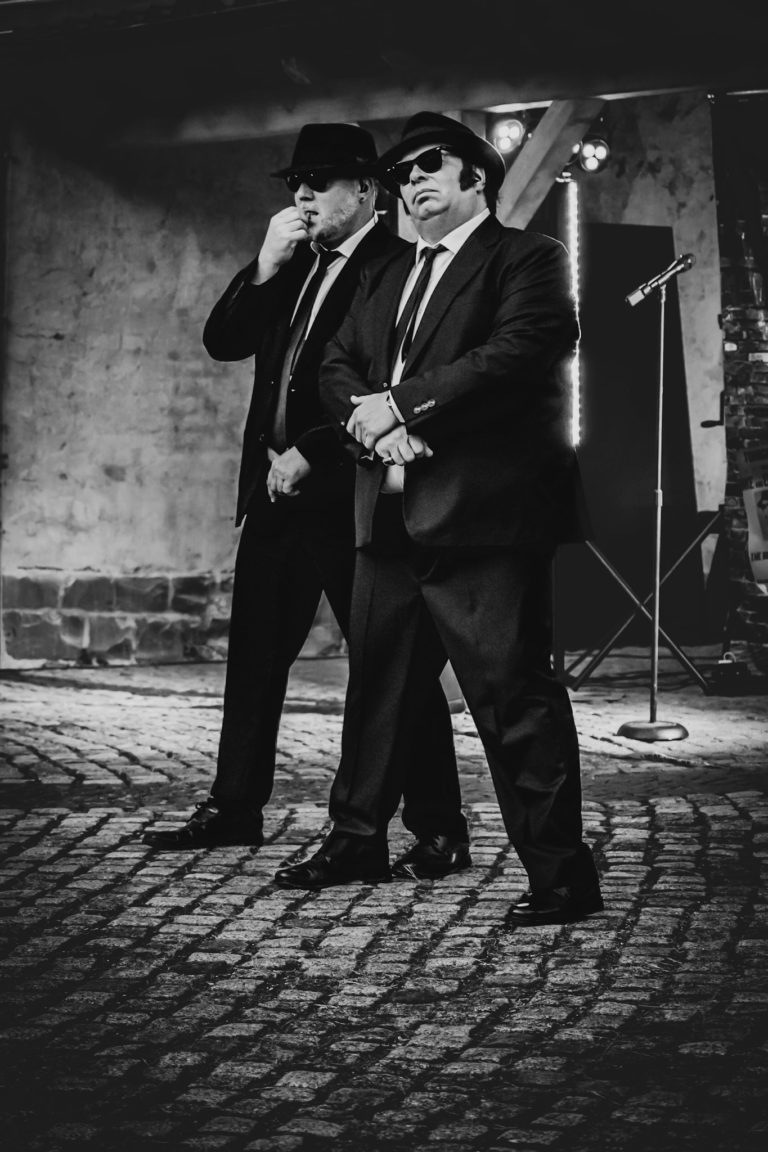 Erleben Sie die Blues Brothers Show von SAT.1 mit „Big Blue“ live! Verwandeln Sie Ihr Event dank der beiden Kulthelden in eine unvergessliche Party. „Jake & Elwood“ (Eddy & George) singen und spielen die größten Hits der legendären Blues Brothers im original Outfit. Die Songauswahl reicht von Everybody Needs Somebody To Love, Soul Man, Rawhide, Shake Your Tail feather bis hin zu Minnie The Moocher und Jailhouse Rock - da ist für jeden etwas dabei! Doch nicht nur die beiden Kulthelden sorgen für Stimmung, auch das Publikum kann sich an der Performance beteiligen: Egal ob bei den gesungenen Refrains oder einem spontanen Tanzeinlage – es herrscht Gänsehautstimmung! „Big Blue“ sind europaweit unterwegs und begeistern mit ihrer energiegeladenen Show immer wieder neue Menschen. Werden Sie zum perfekten Gastgeber und lassen Sie Ihre Gäste/Kunden den 80er-Kultfilm hautnah erleben! Mit „Big Blue“ ist Ihr Event der absolute Hingucker und ein unvergessliches Erlebnis für alle Anwesenden.