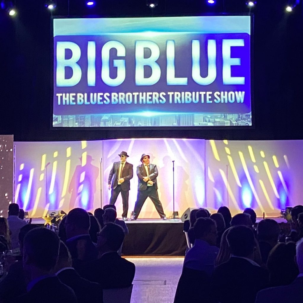 Erleben Sie die Blues Brothers Show von SAT.1 mit „Big Blue“ live! Verwandeln Sie Ihr Event dank der beiden Kulthelden in eine unvergessliche Party. „Jake & Elwood“ (Eddy & George) singen und spielen die größten Hits der legendären Blues Brothers im original Outfit. Die Songauswahl reicht von Everybody Needs Somebody To Love, Soul Man, Rawhide, Shake Your Tail feather bis hin zu Minnie The Moocher und Jailhouse Rock - da ist für jeden etwas dabei! Doch nicht nur die beiden Kulthelden sorgen für Stimmung, auch das Publikum kann sich an der Performance beteiligen: Egal ob bei den gesungenen Refrains oder einem spontanen Tanzeinlage – es herrscht Gänsehautstimmung! „Big Blue“ sind europaweit unterwegs und begeistern mit ihrer energiegeladenen Show immer wieder neue Menschen. Werden Sie zum perfekten Gastgeber und lassen Sie Ihre Gäste/Kunden den 80er-Kultfilm hautnah erleben! Mit „Big Blue“ ist Ihr Event der absolute Hingucker und ein unvergessliches Erlebnis für alle Anwesenden.